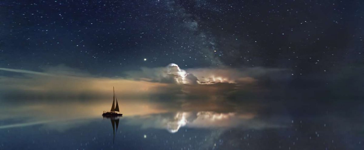Sail boat on smooth water reflecting the night sky